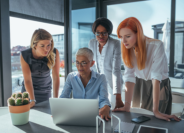 Key People Hero Women team looking at a laptop in an office